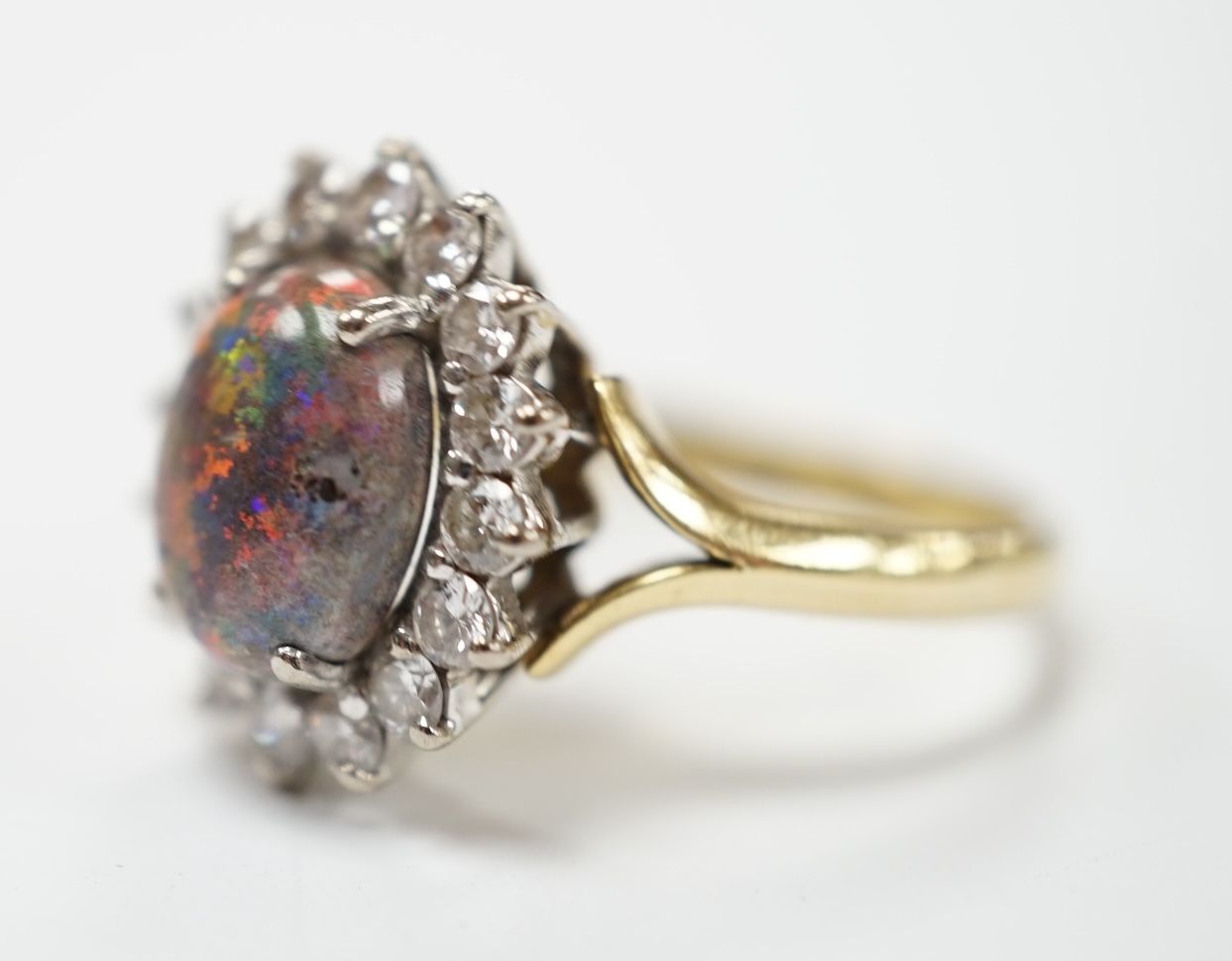 An 18ct, black opal and diamond set oval cluster ring, size P/Q, gross weight 5.4 grams. Fair condition.